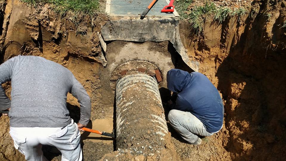 Crew digging out and resetting a broken concrete stormwater pipe