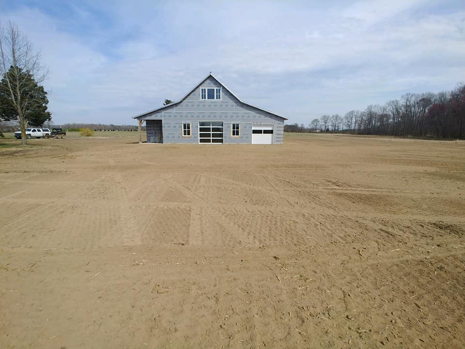 Cleared and graded field in front of a new barn
