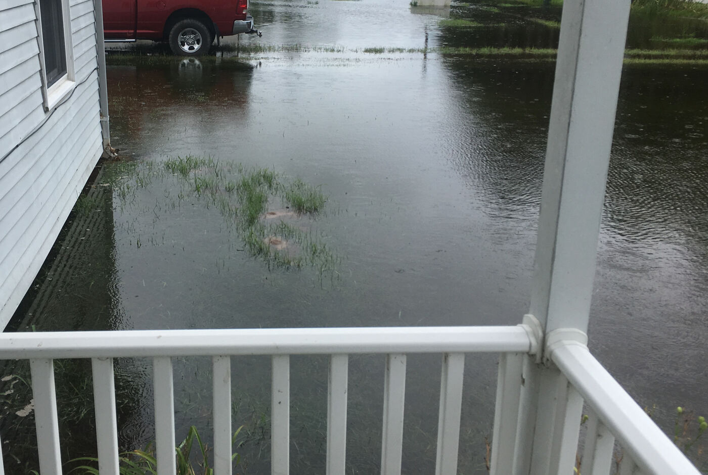 Tidal flood water covering a yard and driveway up to the edge of a porch on the Eastern Shore