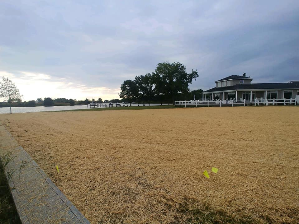 Fresh seed and straw spread across a waterfront lawn by the bulkhead